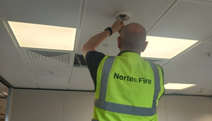 Member of the Nortec Fire team installing a smoke detector in a commercial premises. 